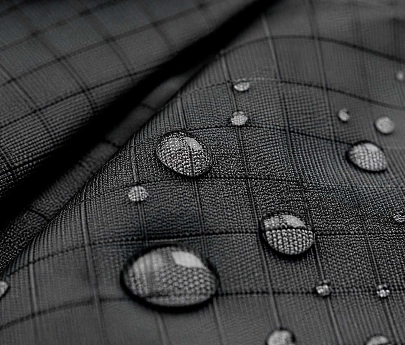 Macro close-up of technical ripstop performance fabric with water beading on the surface